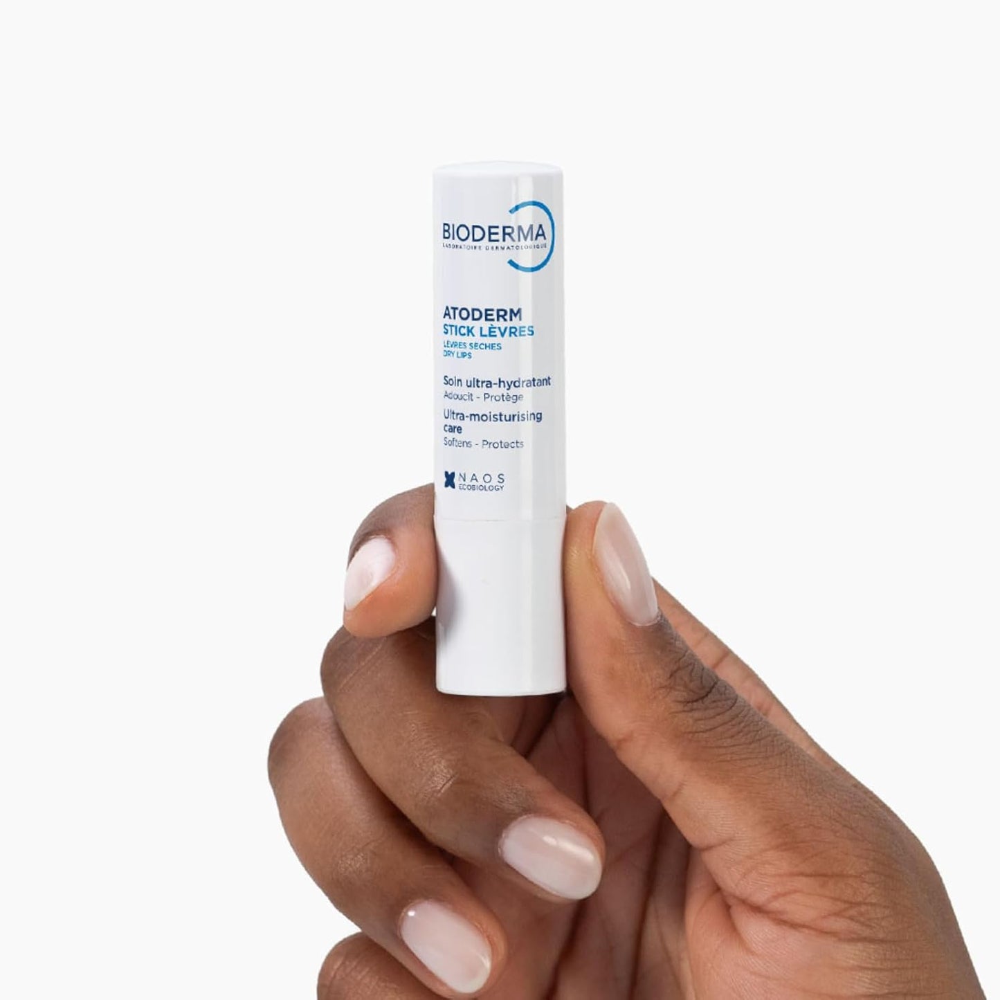Hand holding a Bioderma lip balm against a white background