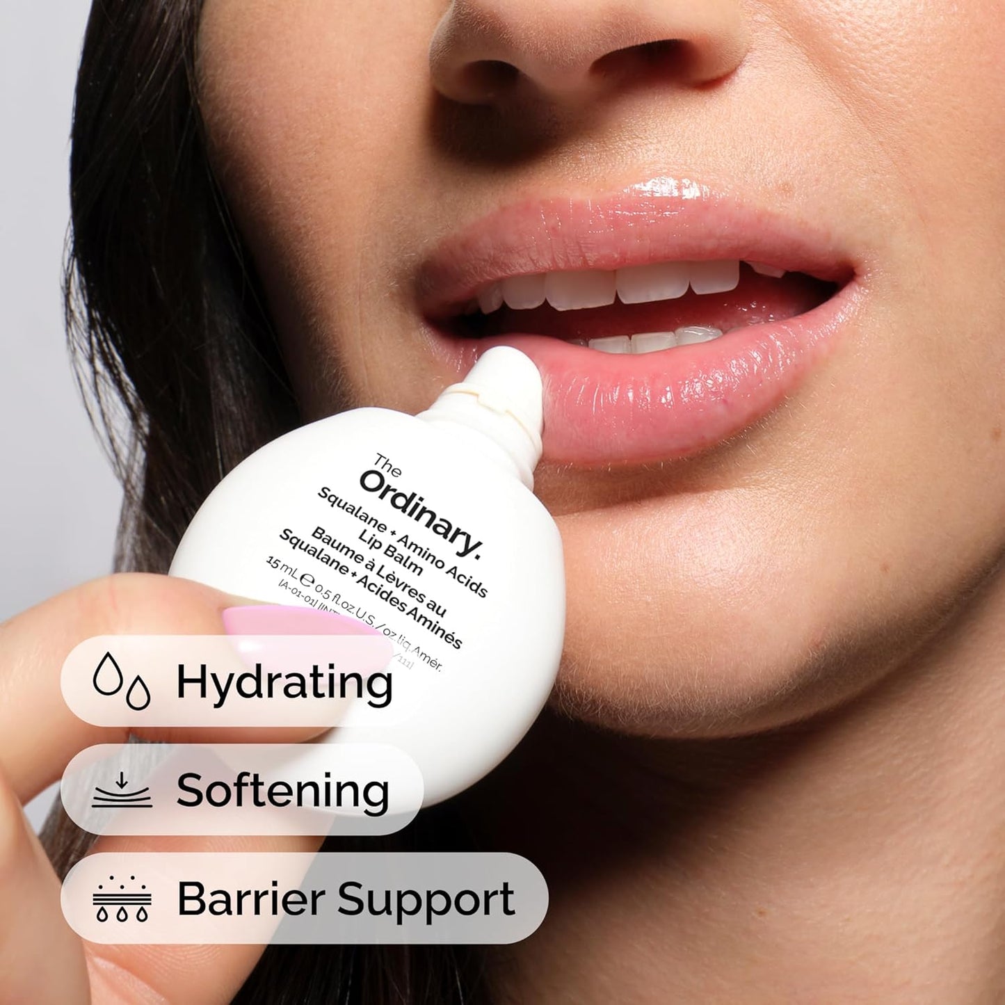 Person applying a lip balm labeled 'The Ordinary' to their lips with text indicating benefits.