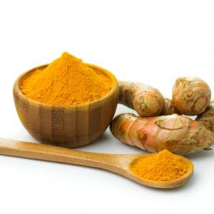 Turmeric root and powder in a wooden spoon and bowl on a white background