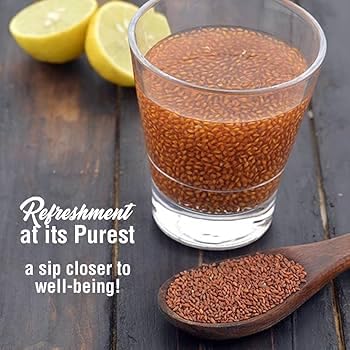 Glass of flaxseed drink with lemons and a spoonful of seeds on a wooden surface.