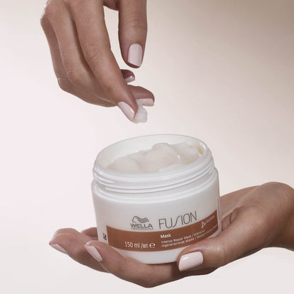 Hand holding a jar of Wella Fusion hair mask with a blurred background