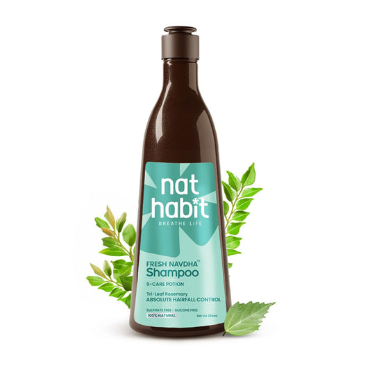 Bottle of nat habit Fresh Navdha Shampoo with green leaves on a white background