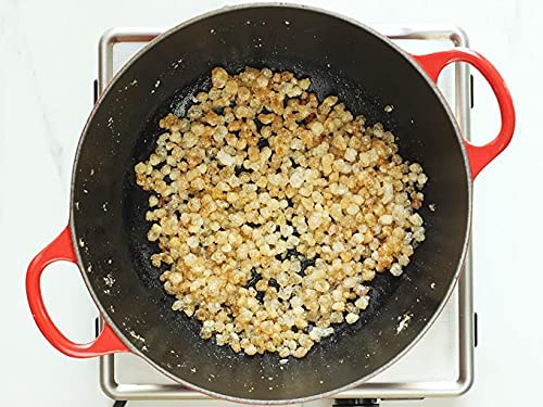 Cooking process of ghee in a red-handled frying pan on a stove.
