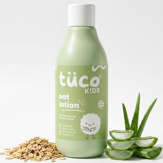 Green bottle of tüco Kids oat lotion with oats and aloe vera leaves on a white background