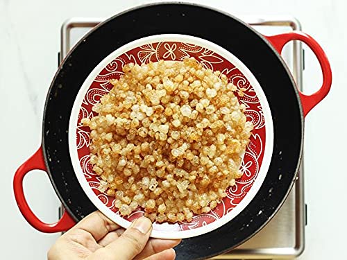 Red and white patterned plate with quinoa held by a hand over a white background