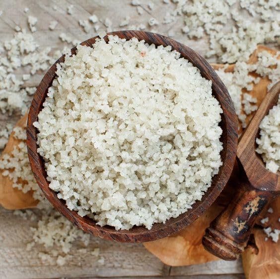 Wooden bowl filled with white granulated product on a wooden surface