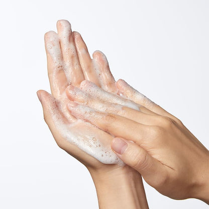 Hands with soap suds on a plain background