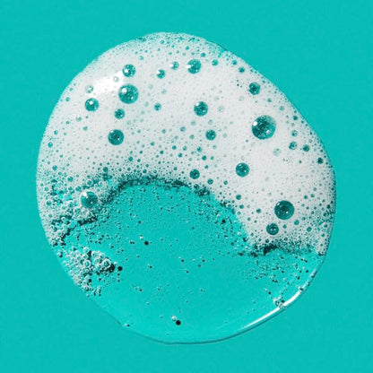 Close-up of a turquoise liquid with bubbles on a teal background