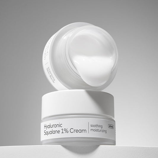 White skincare cream jar with open lid on a gray background