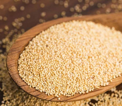 Wooden scoop filled with quinoa seeds on a textured background