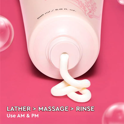 Pink shampoo bottle with foamy texture on a pink background, showing lathering process.