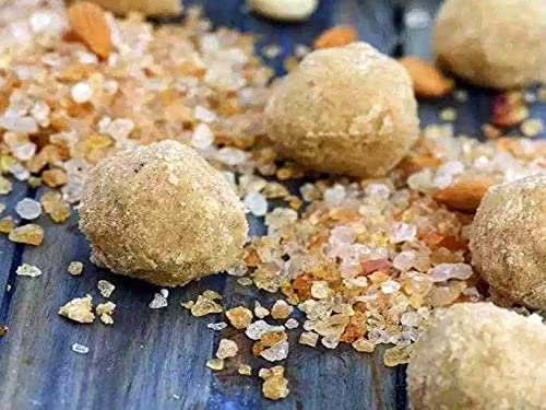 Close-up of round, beige-colored food items on a blue surface with small stones and seeds.