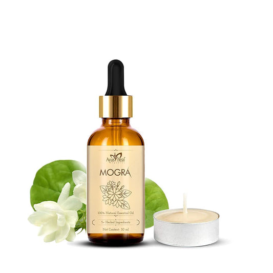 A bottle of Mogra essential oil with a dropper, surrounded by green leaves and a white flower on a white background.