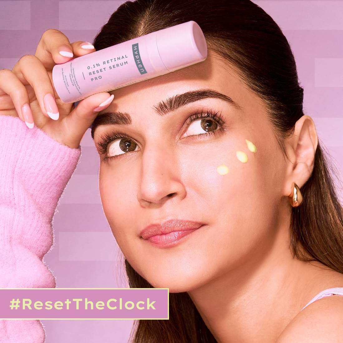 Woman holding a skincare product with a pink background