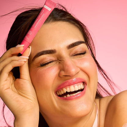 Woman holding a pink skincare product against a pink background