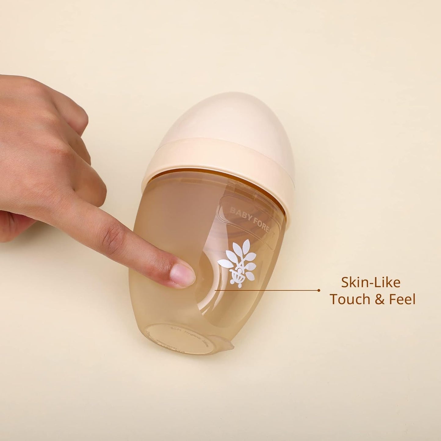 Hand touching a baby bottle with 'Skin-Like Touch & Feel' text on a beige background