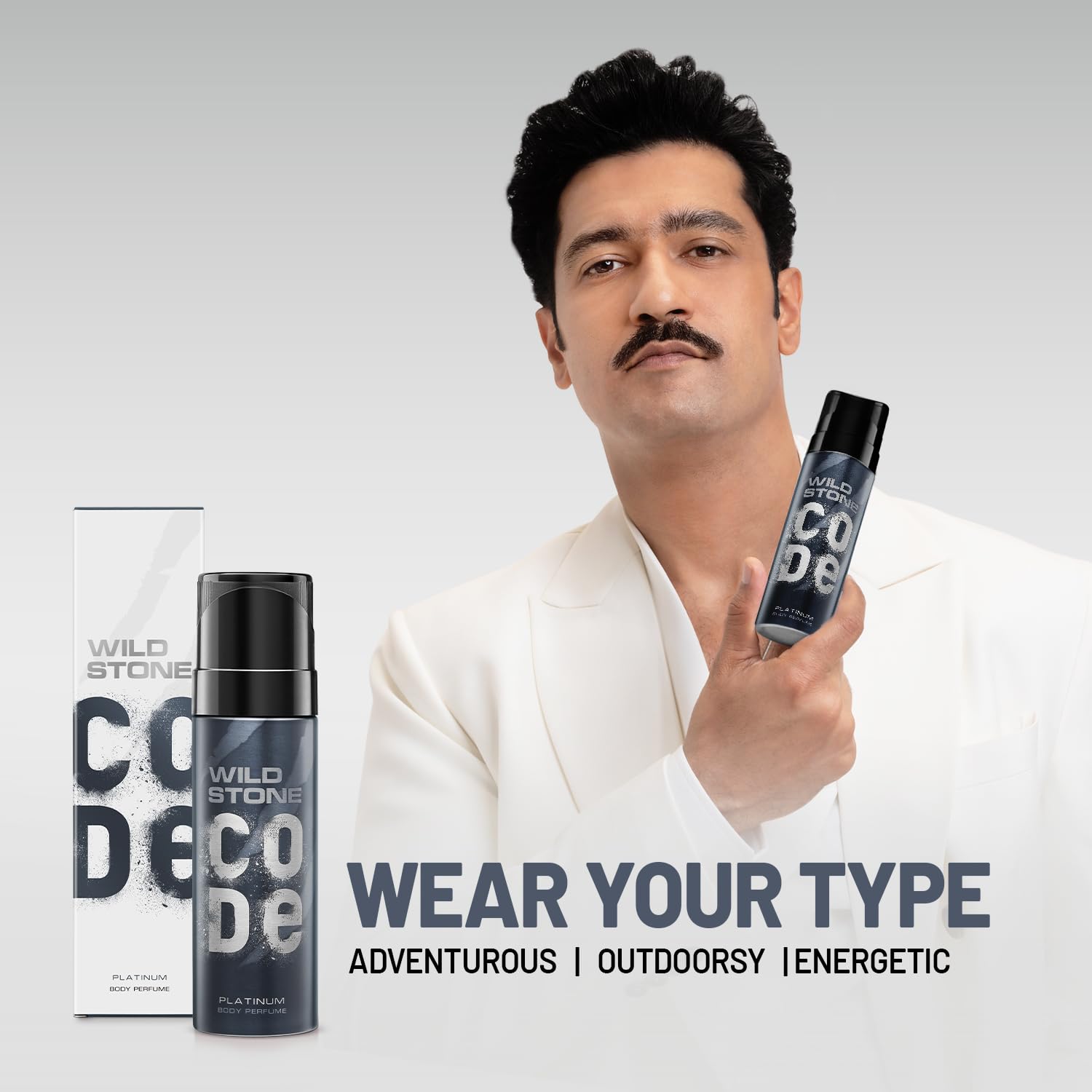 Man holding Wild Stone Code deodorant with product packaging on a gray background