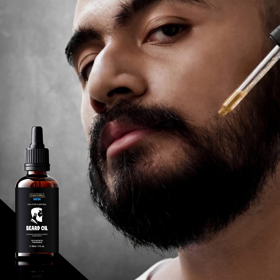 Man with a beard and a bottle of beard oil on a dark background