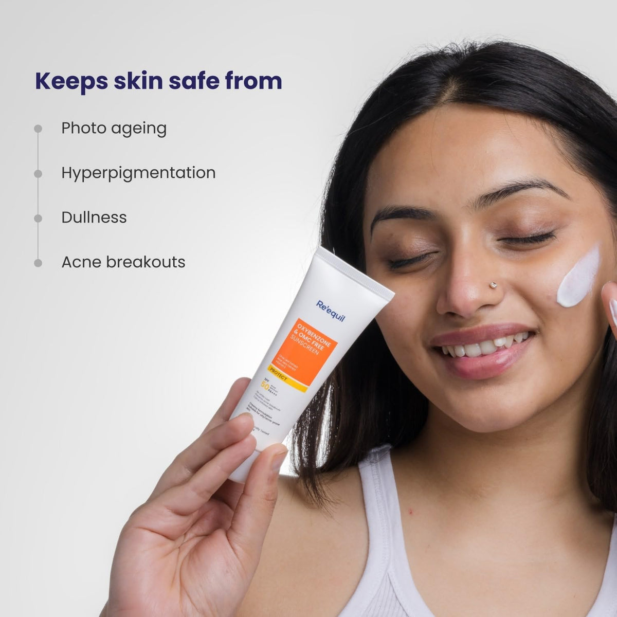 Woman applying sunscreen cream with a tube labeled 'Balea' on a light gray background.