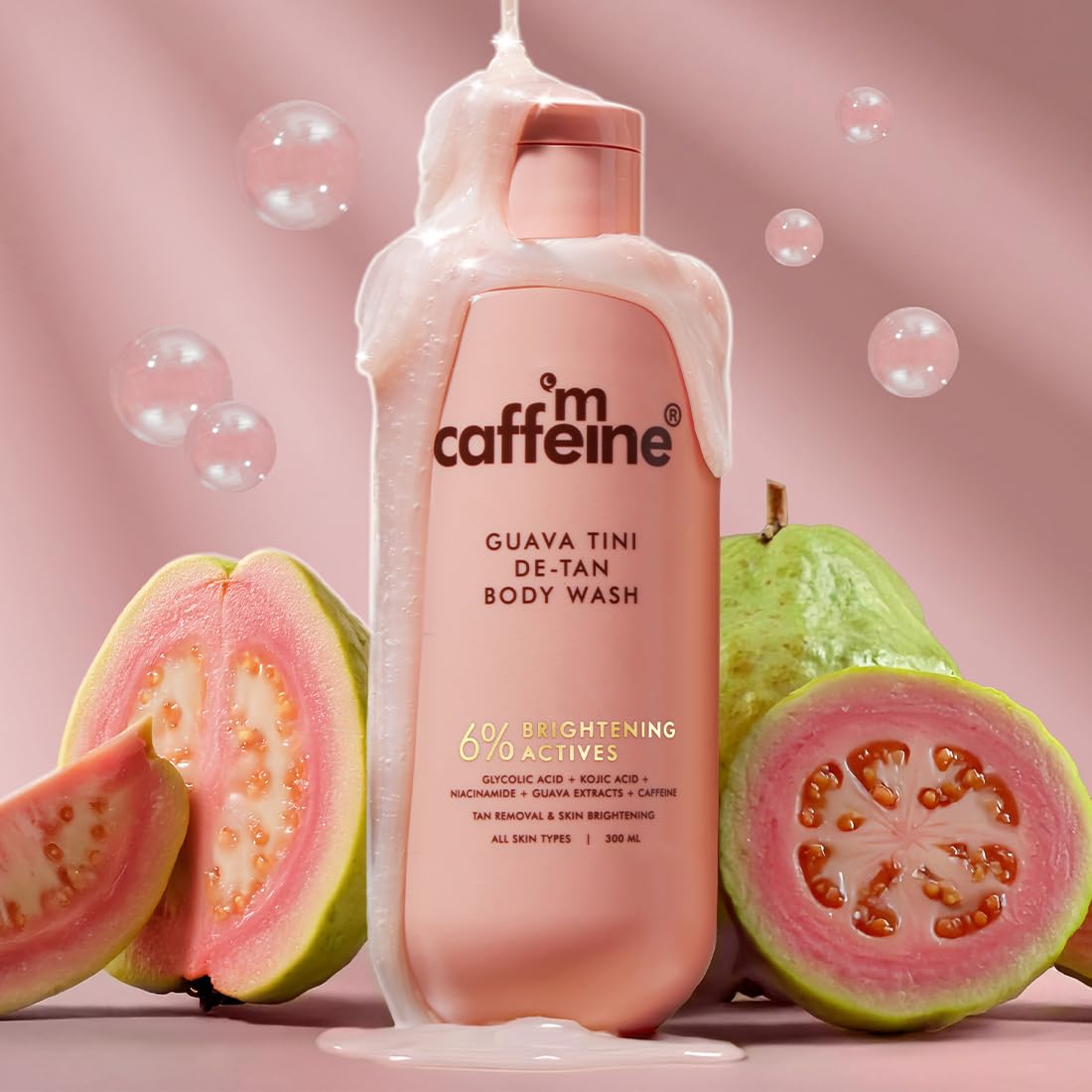 Caffeine Guava Tini De-Tan Body Wash bottle with guava fruits on a pink background