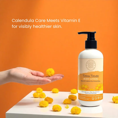Hand holding calendula flowers with a bottle of Calming Calendula Hand Lotion on an orange background