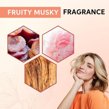 Advertisement for fruity musky fragrance with a woman and floral, wood, and fruit elements on a pink background.