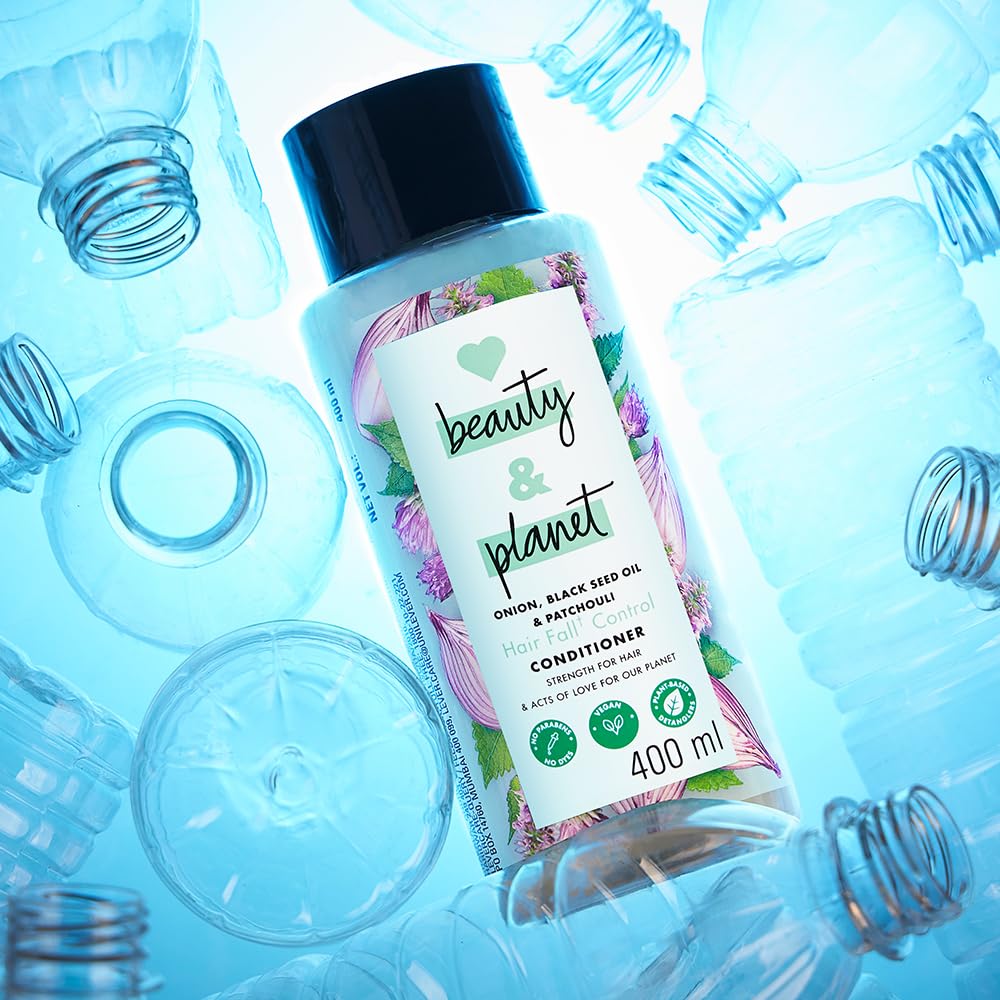Bottle of 'beauty & planet' conditioner surrounded by empty bottles on a blue background