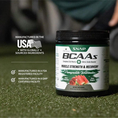 Supplement container labeled 'SNAP BCAAs' on a grassy field background