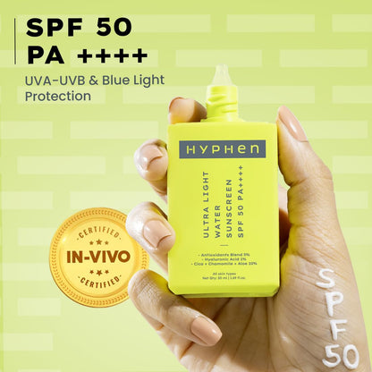 Hand holding a yellow HYPHEN sunscreen bottle with SPF 50 on a green background