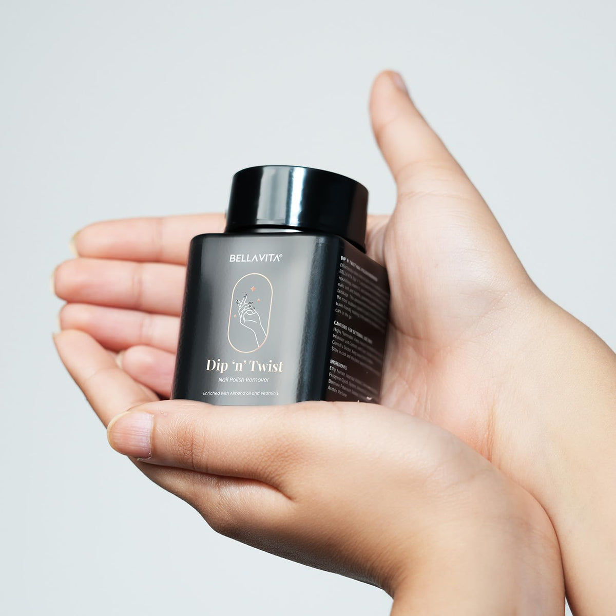 Hand holding a black bottle labeled 'Dip 'n' Twist' against a gray background