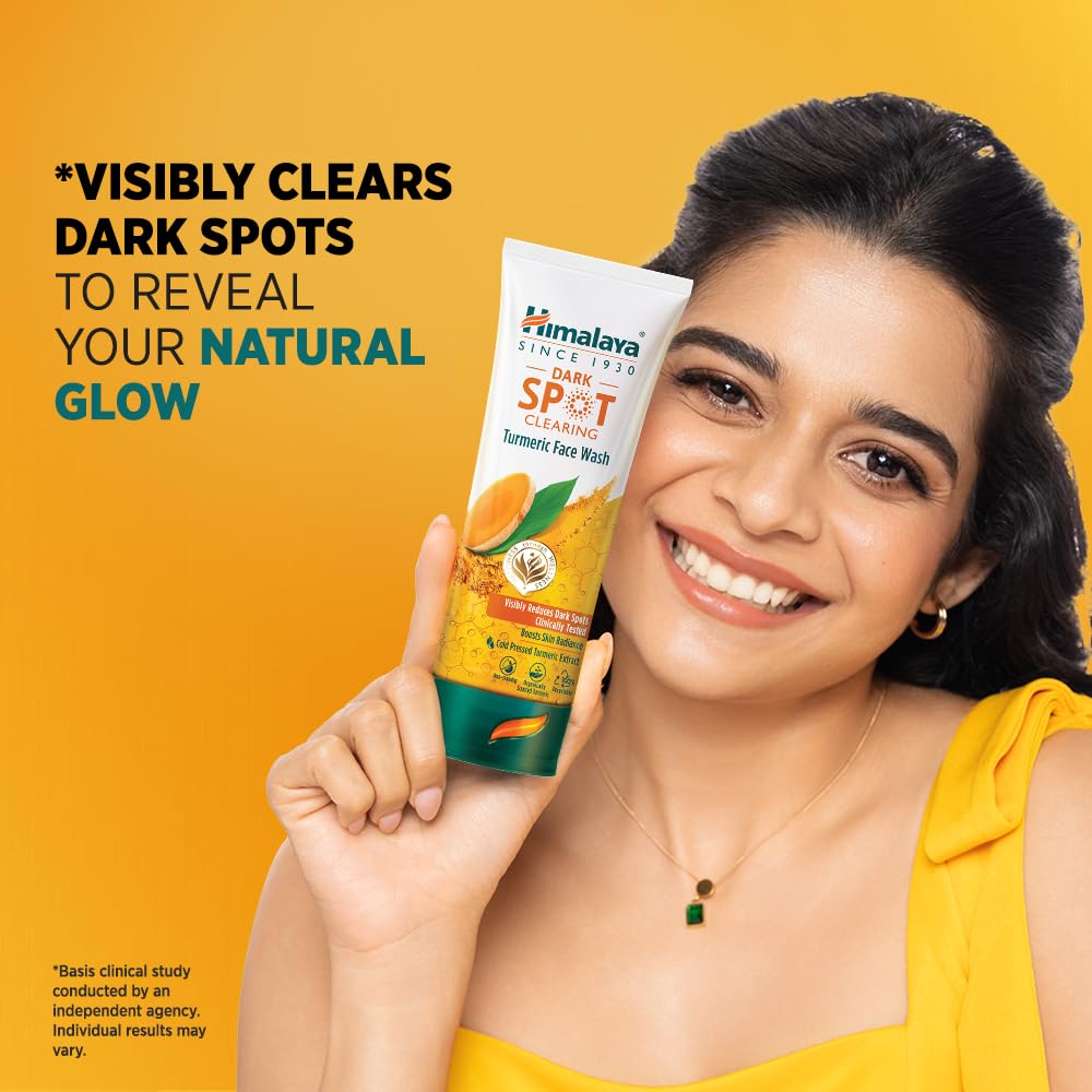 Woman holding a Himalaya Dark Spot Clearing product against a yellow background