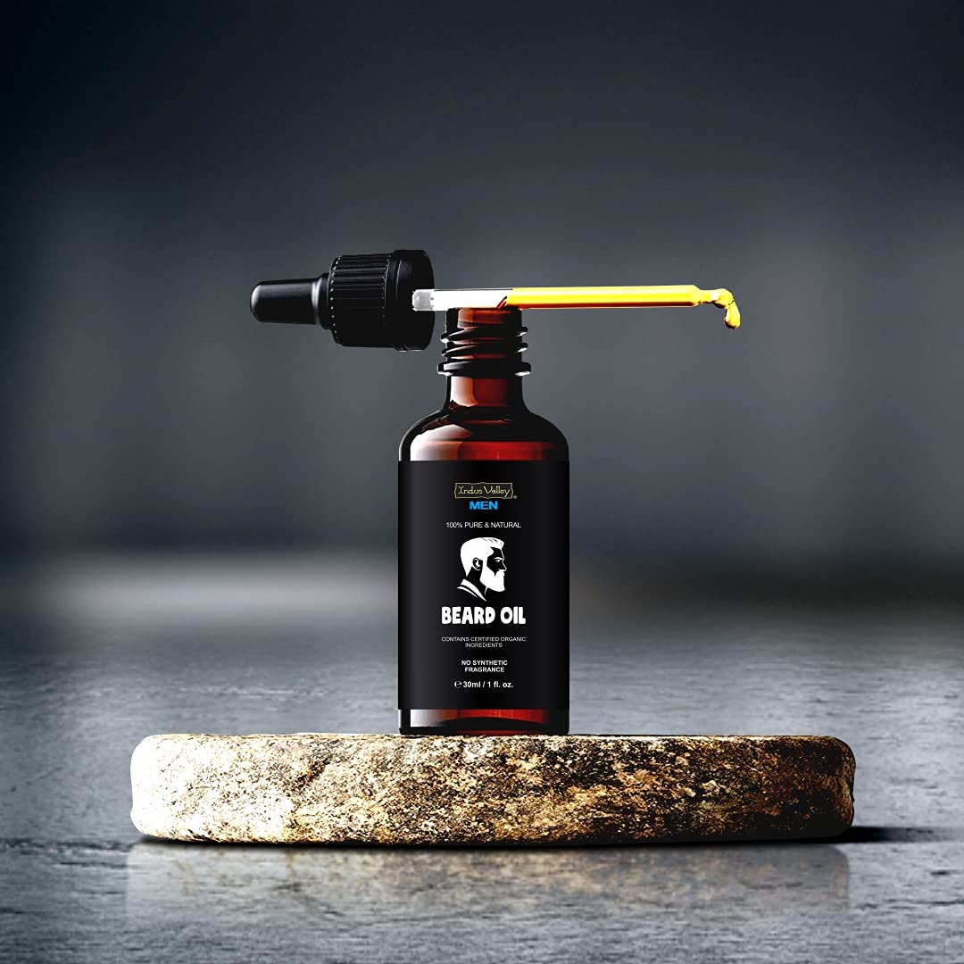 Bottle of beard oil with a dropper on a stone surface against a dark background