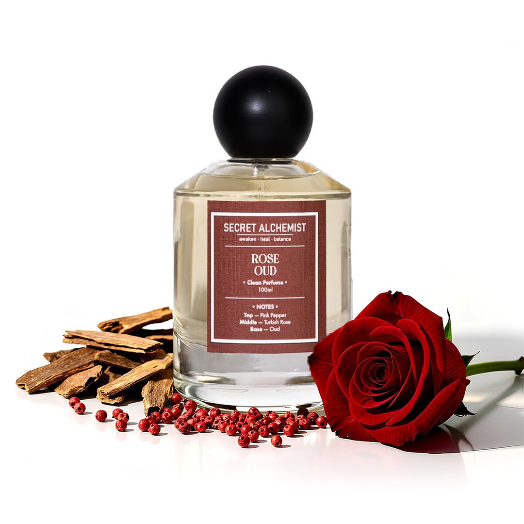 Perfume bottle labeled 'Secret Alchemist Rose Oud' with a red rose and cinnamon sticks on a white background
