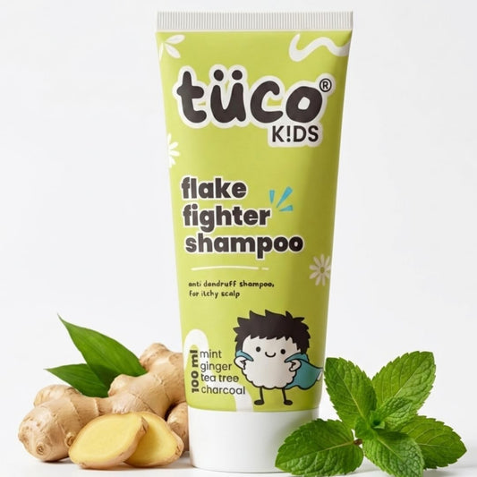 Tube of tüco Kids Flake Fighter Shampoo with ginger and mint leaves on a white background
