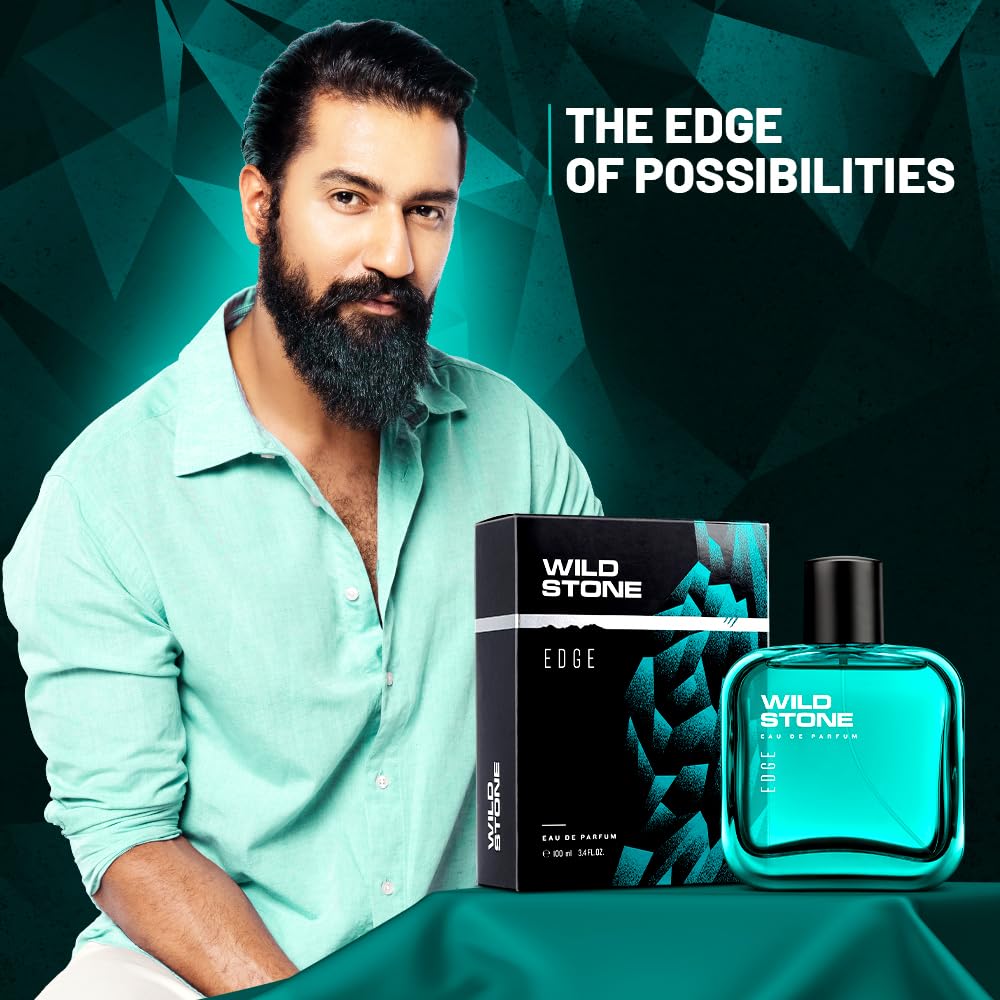 Man with a beard sitting next to Wild Stone Edge perfume bottle and packaging on a green background