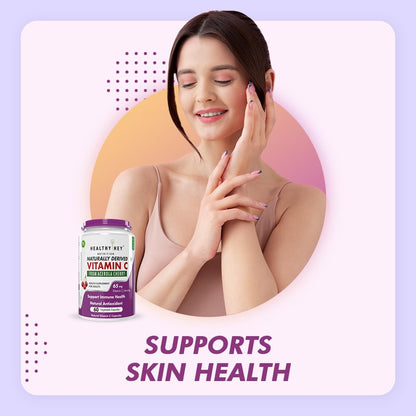 Woman touching her skin with a bottle of Healthy Net Vitamin C supplement on a gradient background