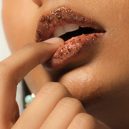 Close-up of a person applying glittery lip product with a finger.