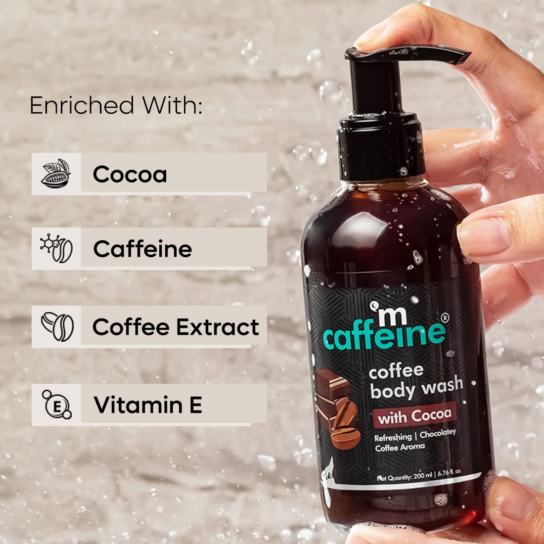 Hand holding a bottle of 'm caffeine coffee body wash with Cocoa' against a gray background.