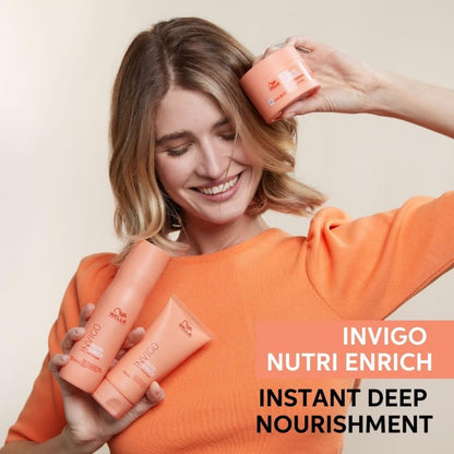 Woman holding Wella Invigo Nutri Enrich hair care products against a beige background