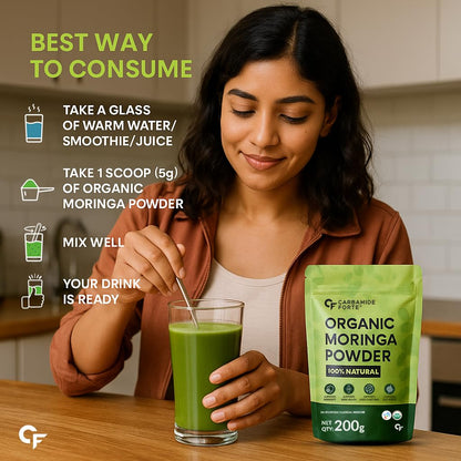 Woman mixing organic moringa powder into a glass of water with a package of organic moringa powder on a wooden table.