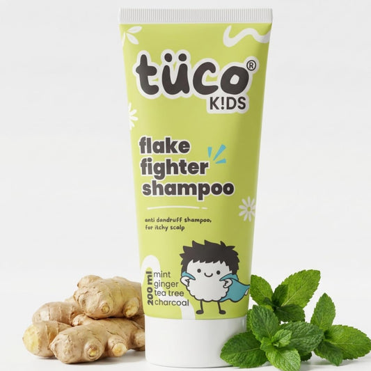 Tube of tüco Kids Flake Fighter Shampoo with ginger, mint leaves, and charcoal on a white background
