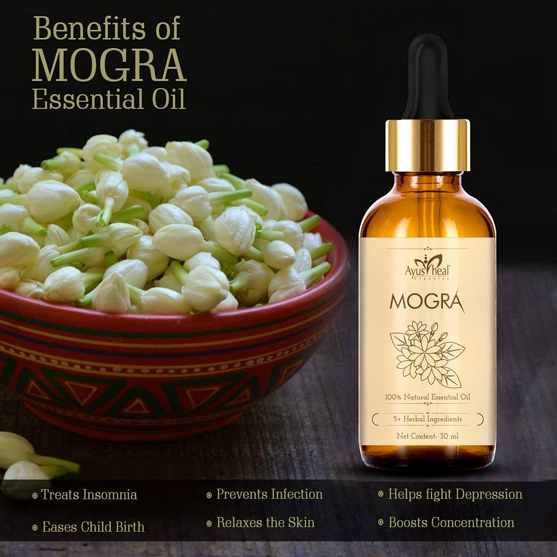 Bottle of Avus Heal Mogra essential oil with a bowl of mogra flowers on a dark background