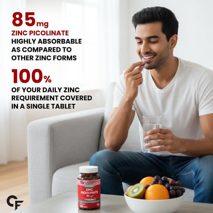 Man holding a glass of water with a bowl of fruits and a supplement bottle on a table, with text about zinc picolinate supplement.