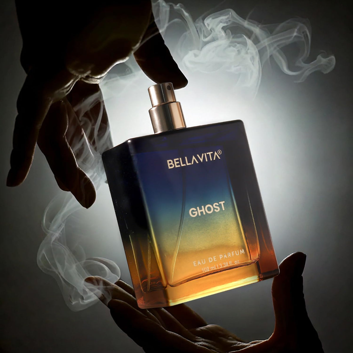 Bellavita Ghost perfume bottle held by a hand with smoke effects on a dark background