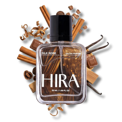 Perfume bottle labeled 'HIRA' surrounded by cinnamon sticks and vanilla beans on a white background