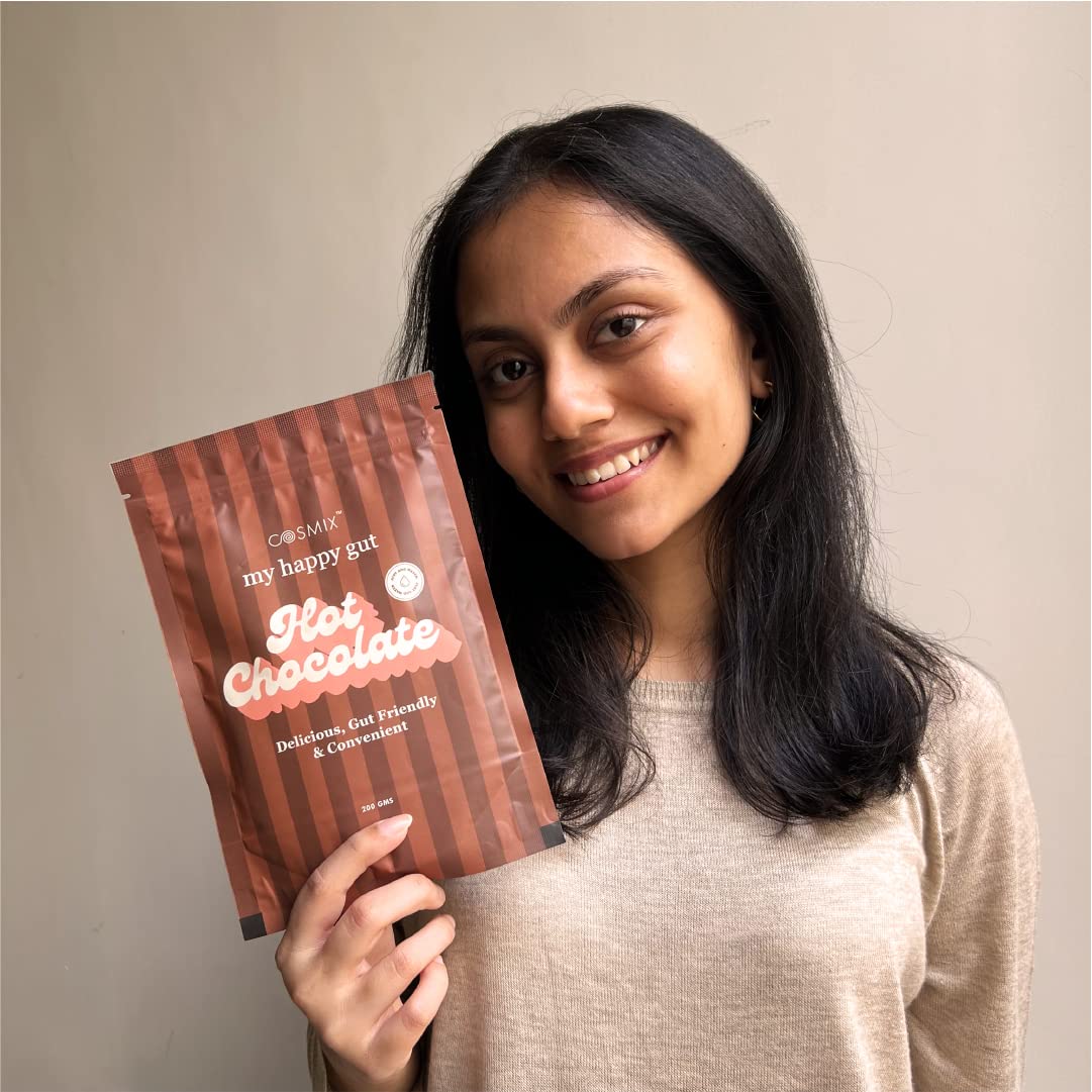 Woman holding a package of 'my happy gut' hot chocolate against a plain background