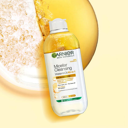 Garnier Micellar Cleansing Water bottle with oil splash on a yellow background