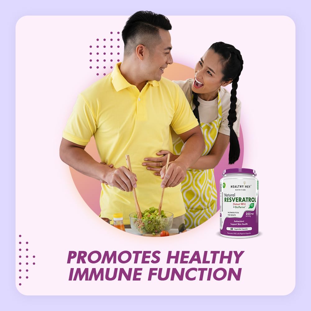 Couple cooking together with a supplement bottle on a light purple background
