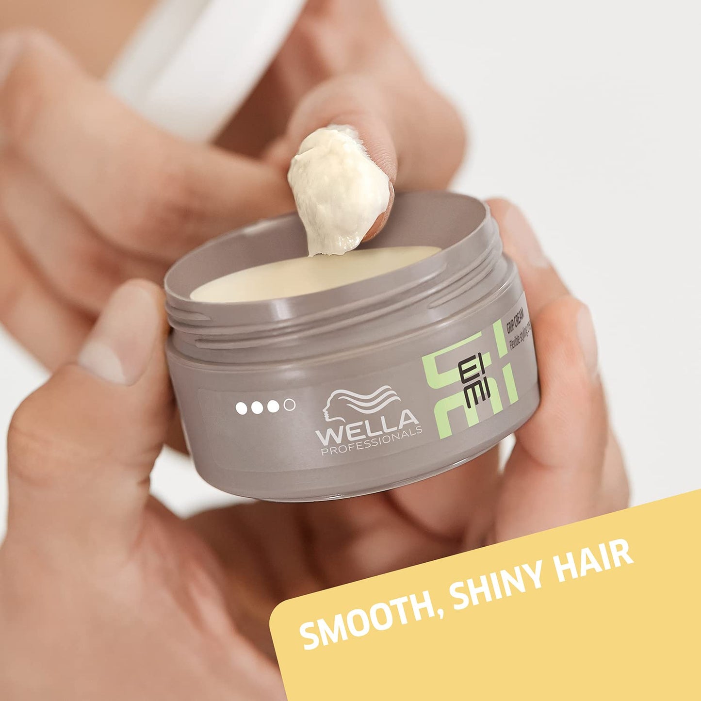 Wella Eimi hair product jar with cream being applied, on a neutral background