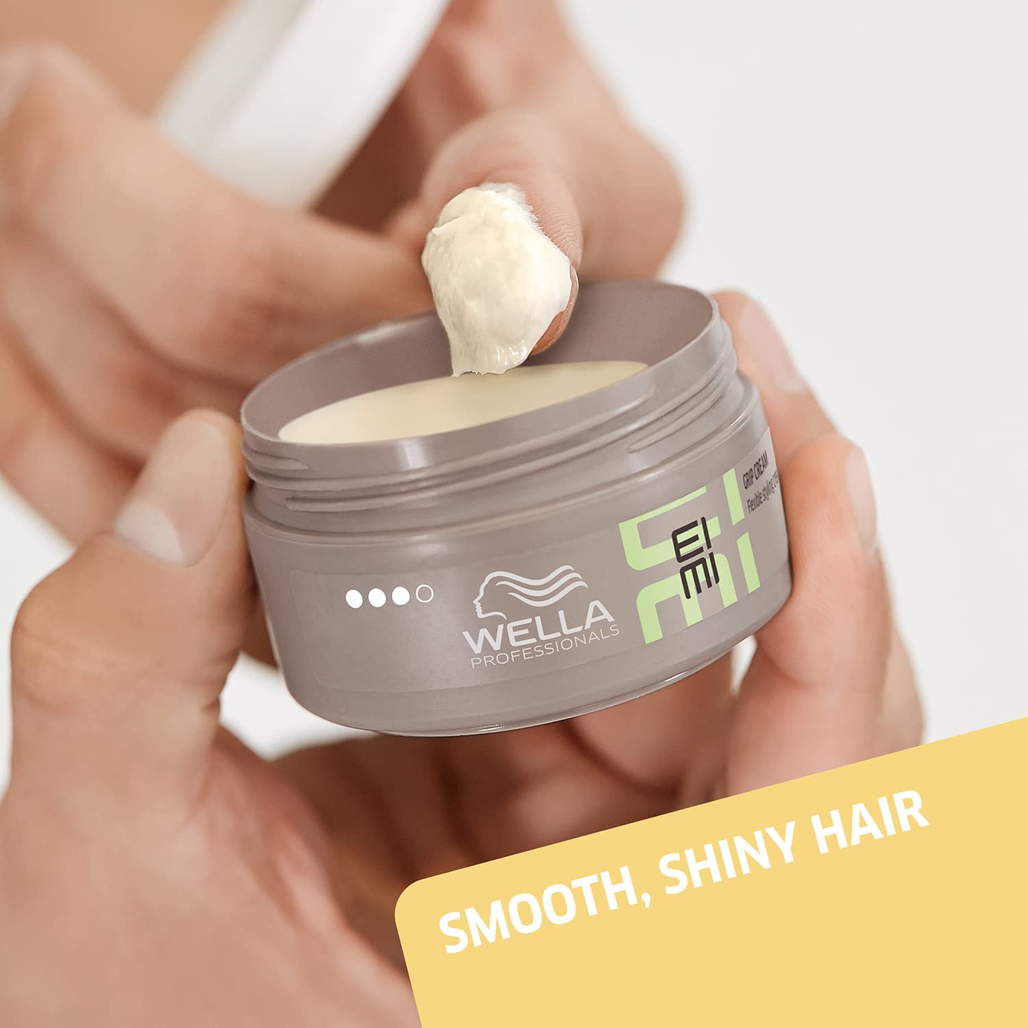 Wella Eimi hair product jar with cream being applied, on a neutral background